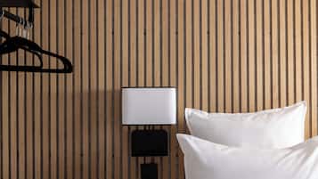 A room with a wooden slat wall, a black wall-mounted lamp, and two white pillows.