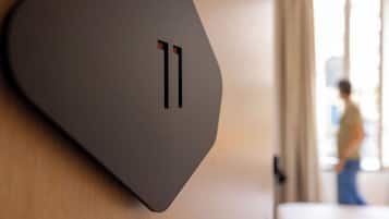A modern, minimalist wall-mounted light switch with a sleek, curved design.