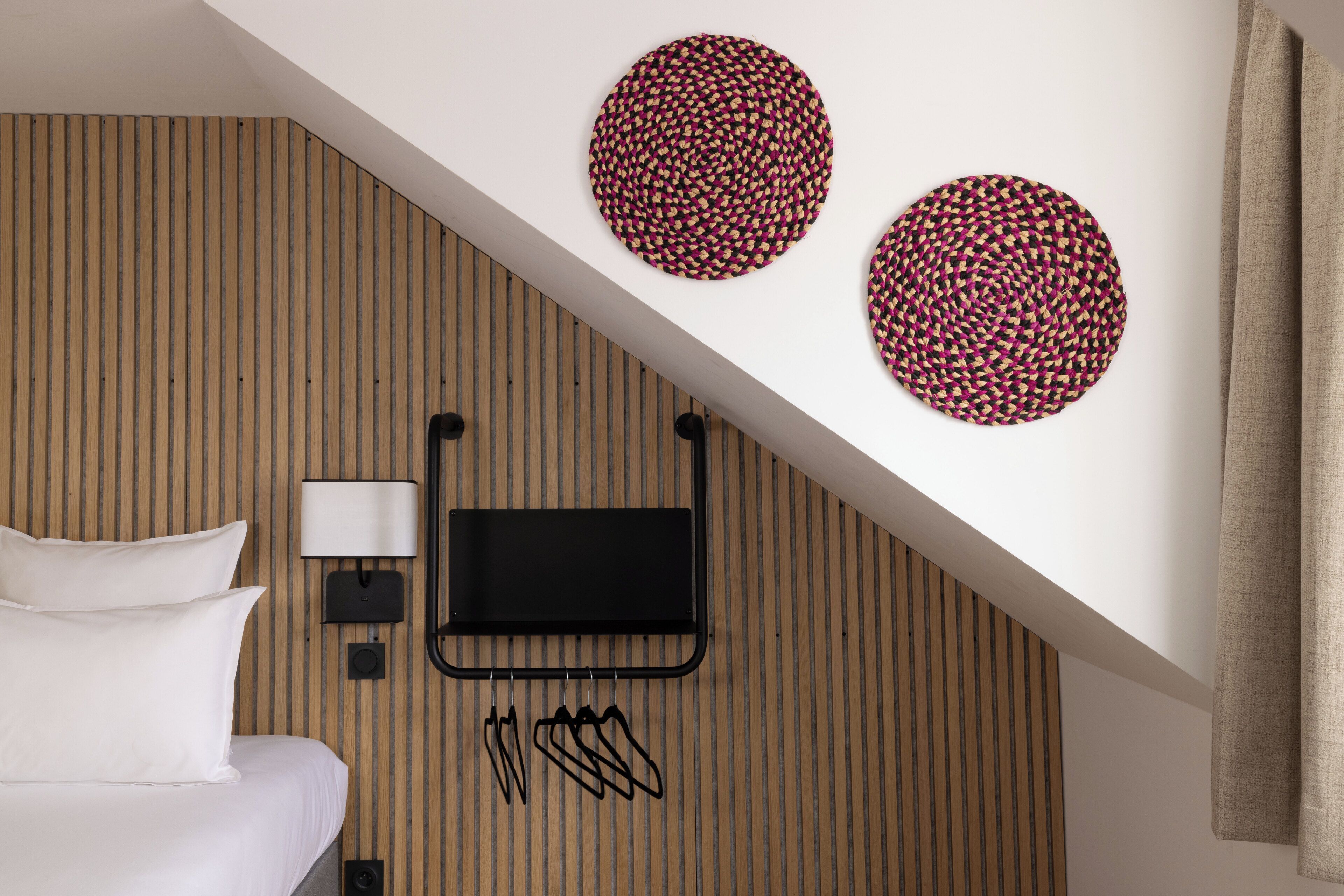 Une chambre d’hôtel avec un lit, un téléviseur fixé au mur et deux éléments de décoration circulaire accrochés au mur.