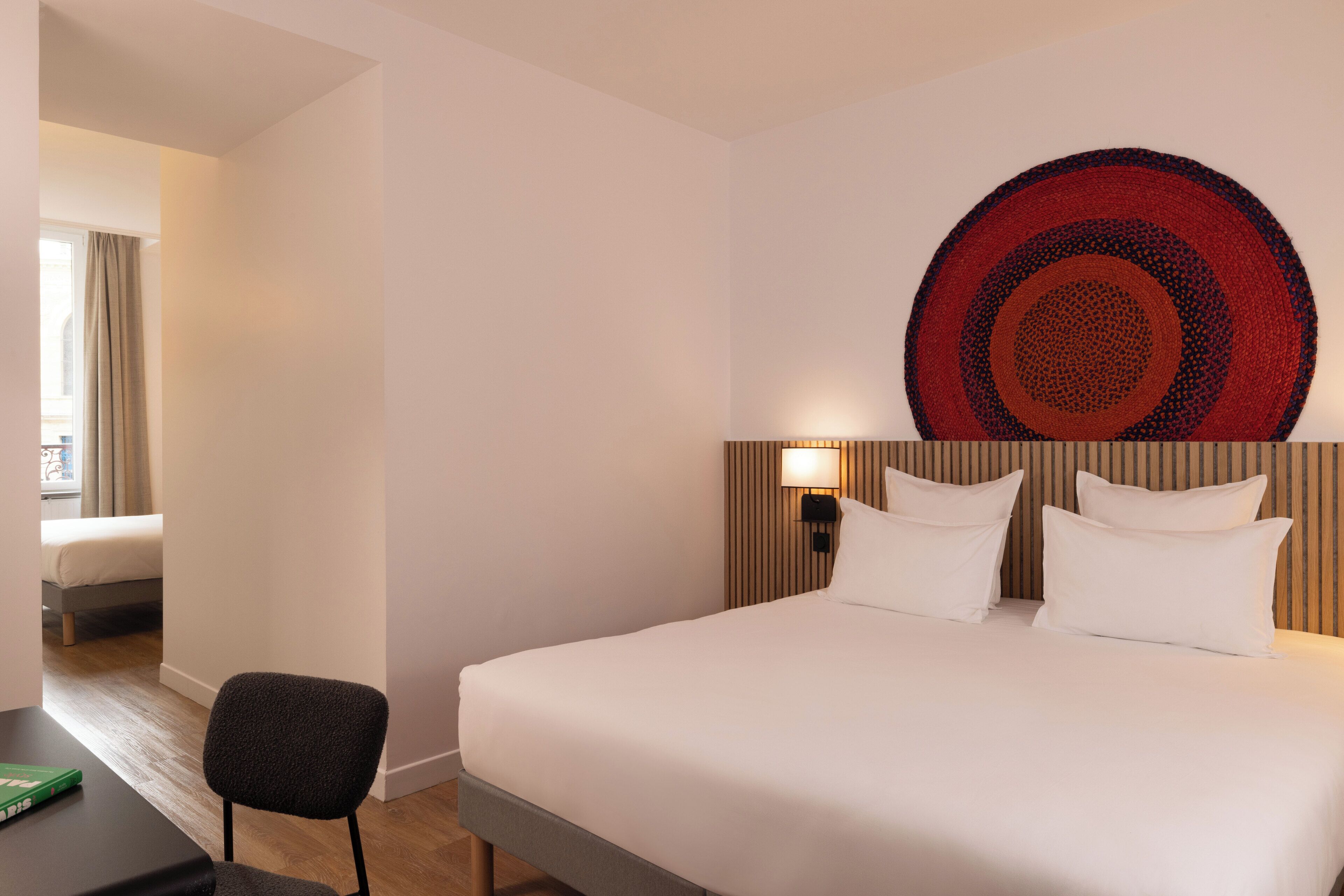 Una habitación de hotel con una cama grande, una silla, un escritorio y una obra de arte en la pared.