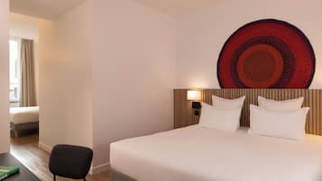 Una habitación de hotel con una cama grande, una silla, un escritorio y una obra de arte en la pared.