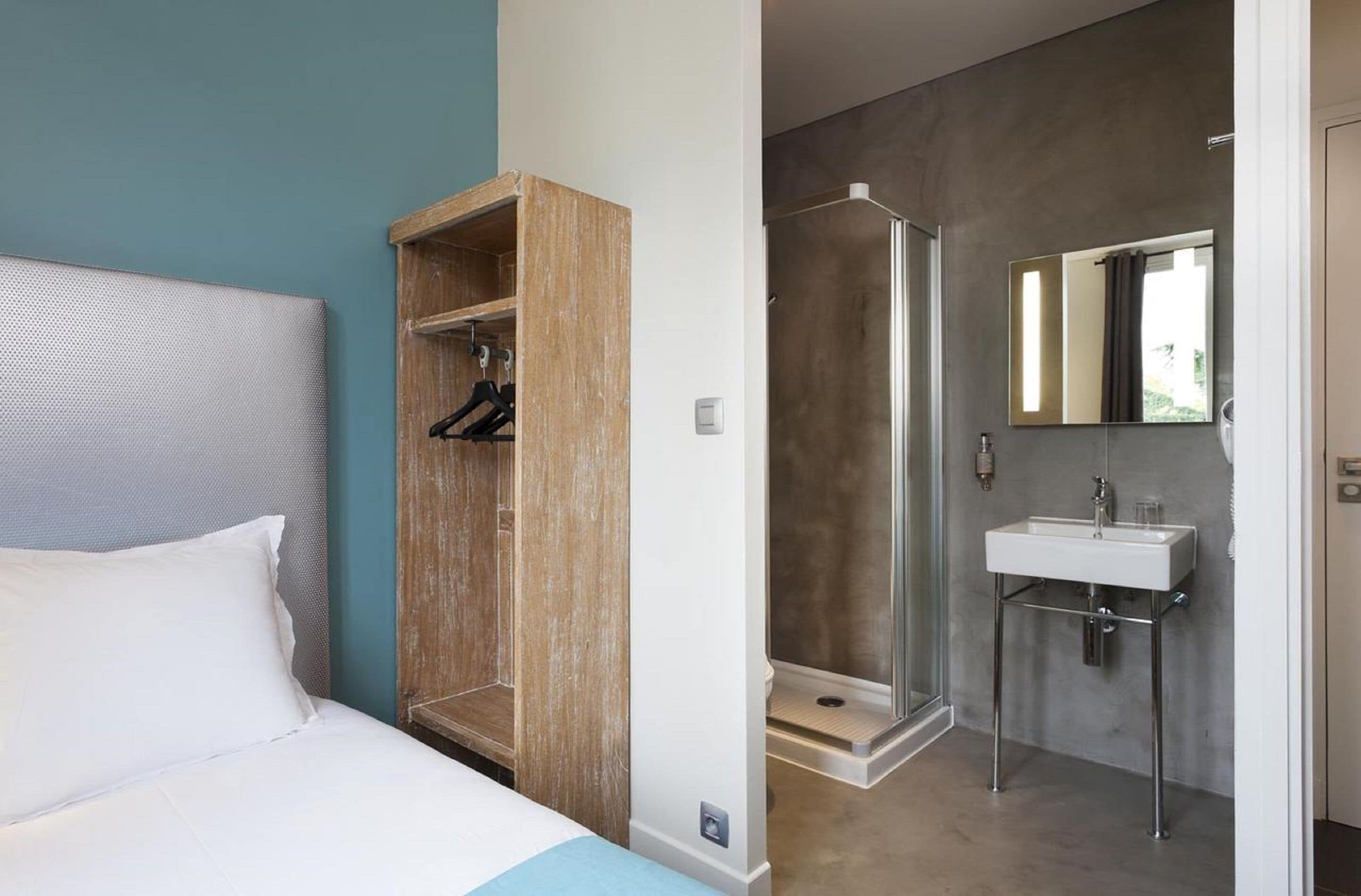 Un dormitorio con cama, armario de madera y baño con ducha y lavabo.