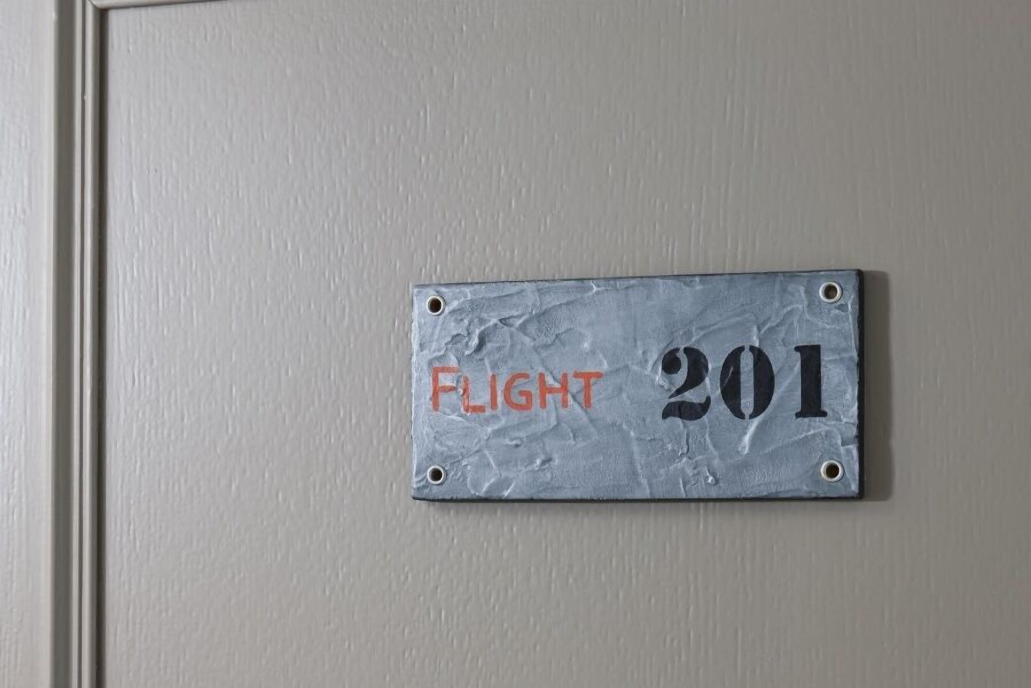 A metal sign with "FLIGHT 201" on a wall.