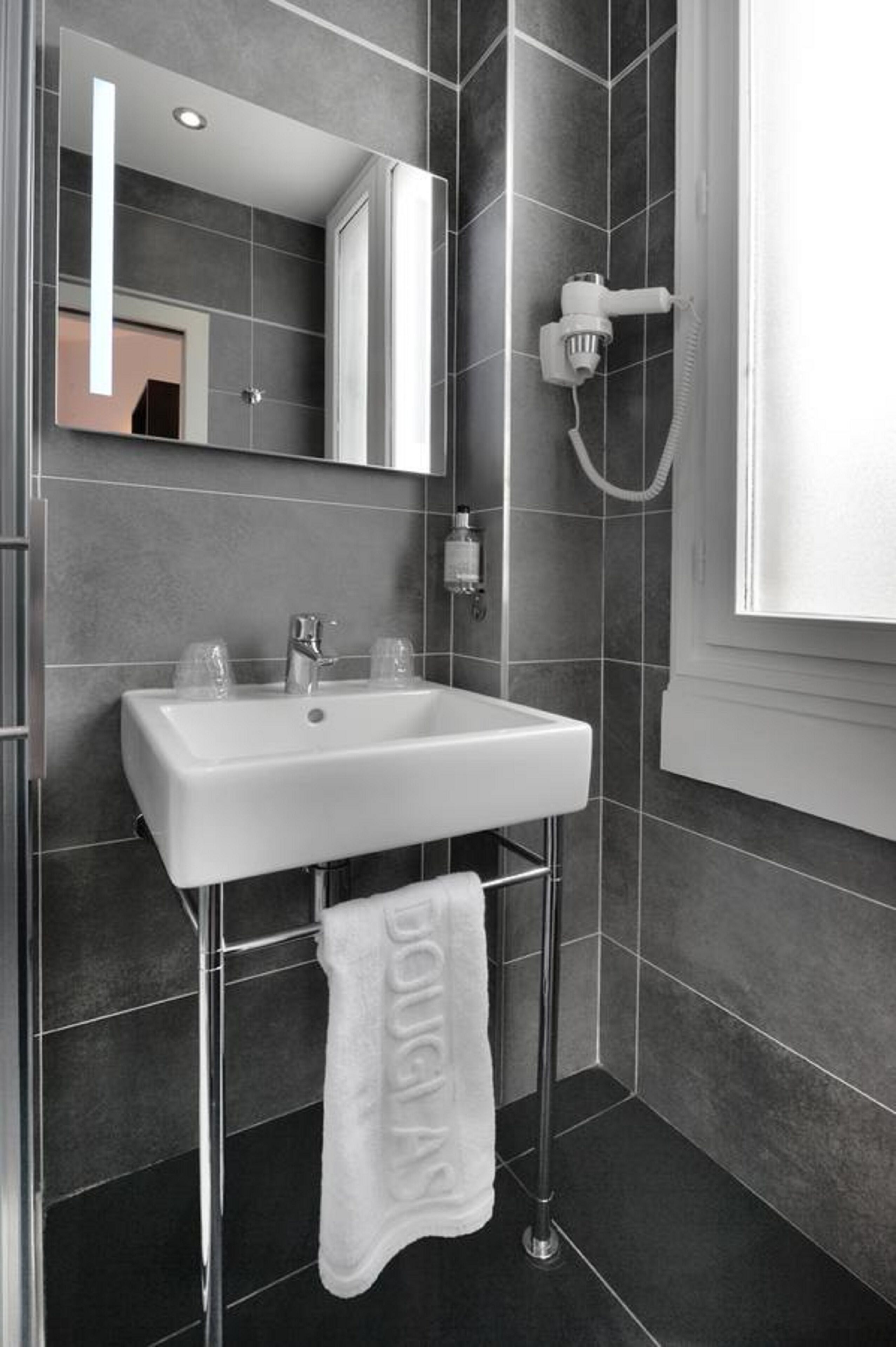 A modern bathroom with a white sink, a towel rack, and a shower head.
