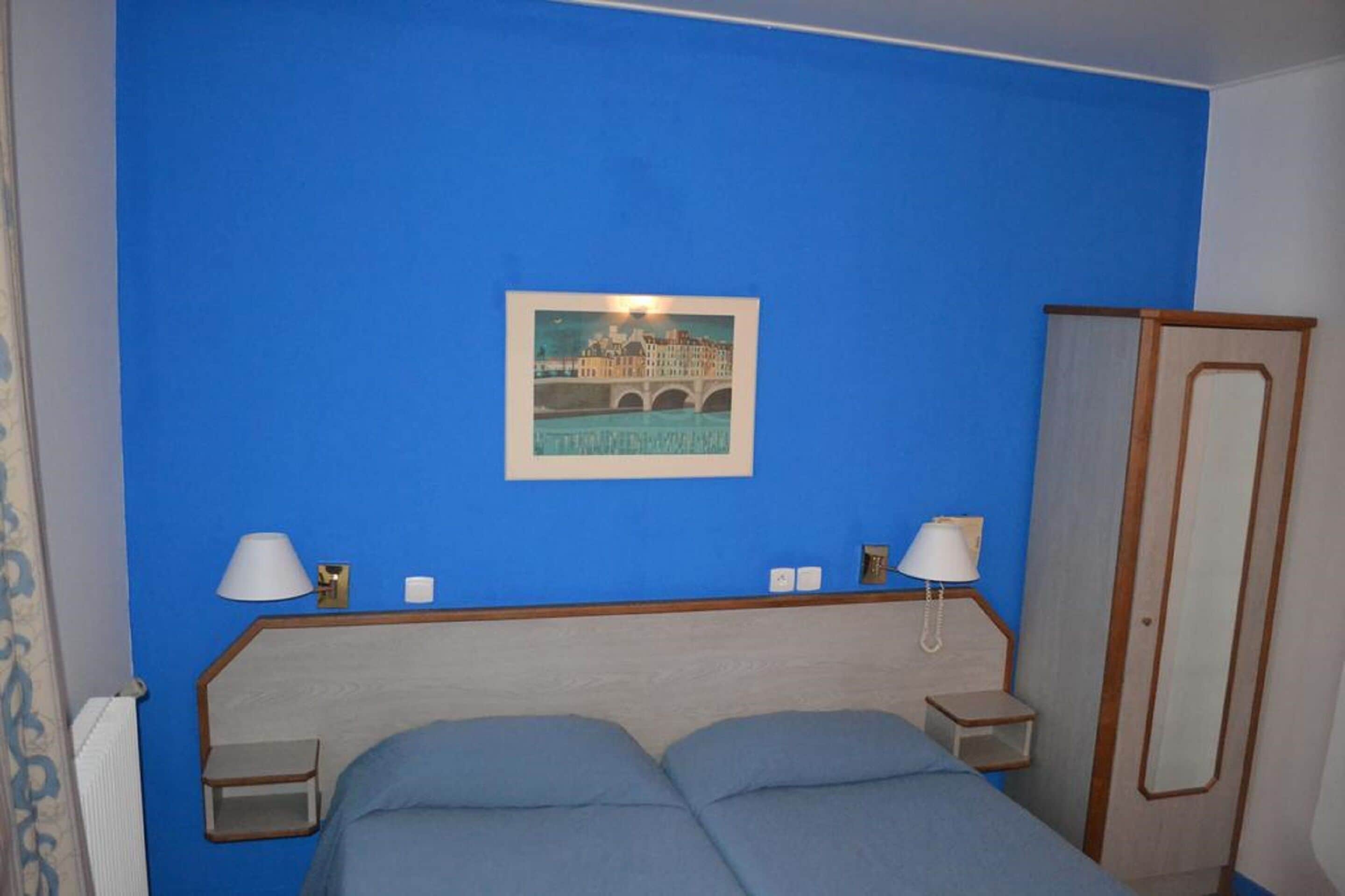 Een kamer met een bed, twee nachtkastjes, een kledingkast en een lijst aan de muur.
