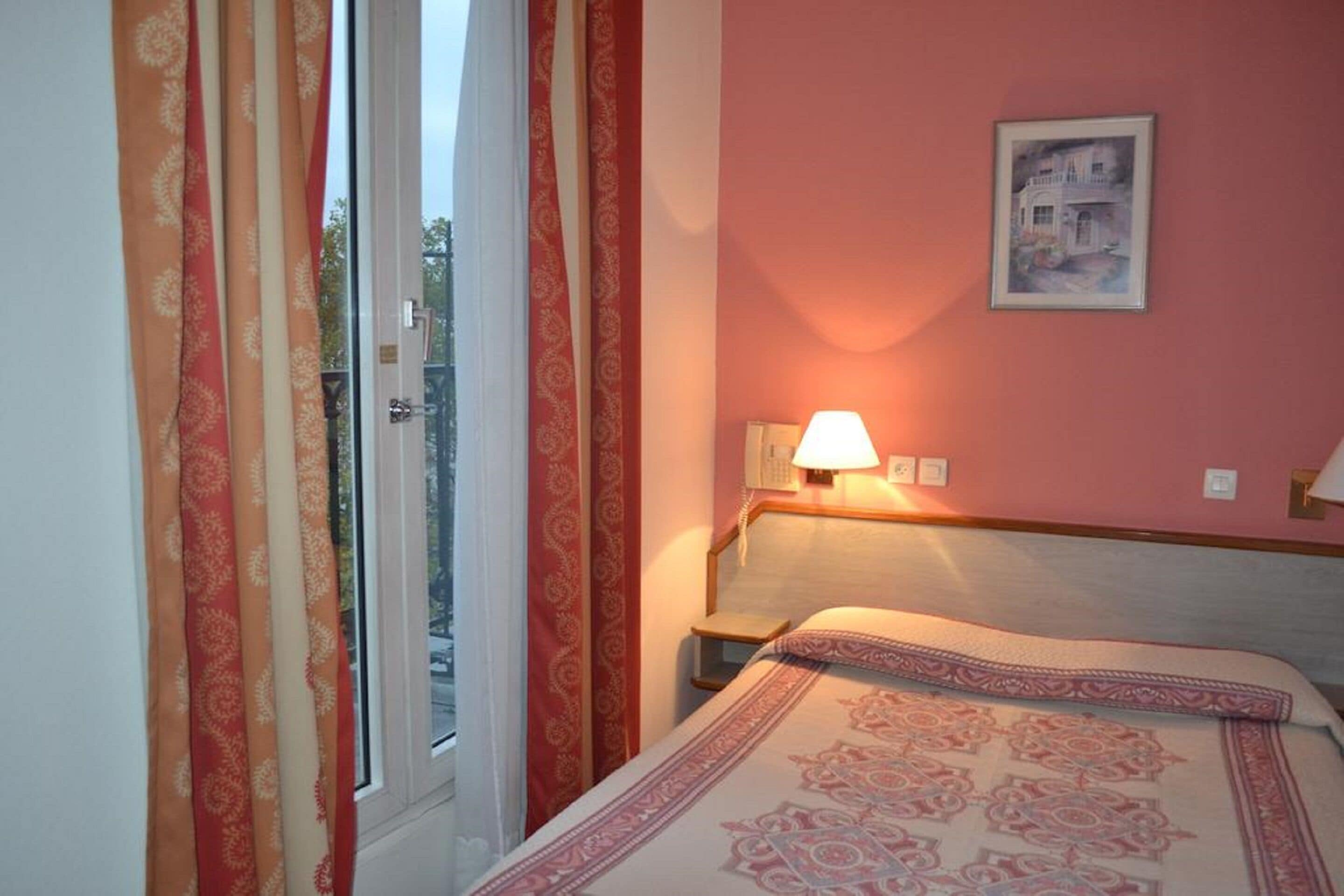 Une chambre à coucher avec un lit, une table de chevet, une lampe et un tableau encadré au mur.