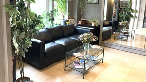 Ein modernes Wohnzimmer mit einem Ledersofa, einem Glastisch mit Zeitschriften und mehreren Blumentöpfen.