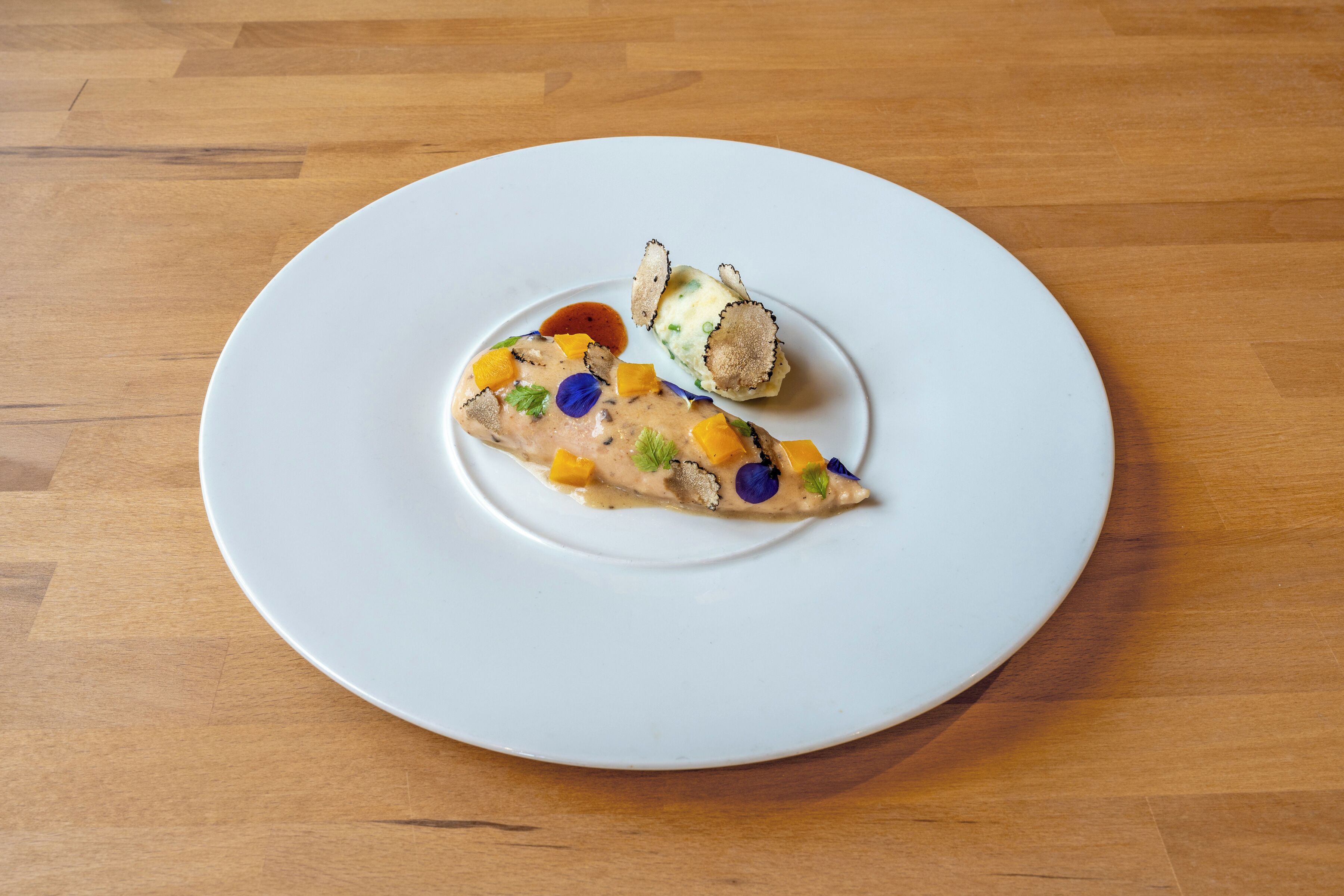 A white plate with a piece of food on a wooden table.