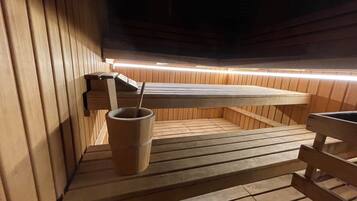 Uma sauna com bancos de madeira e um balde com escova.