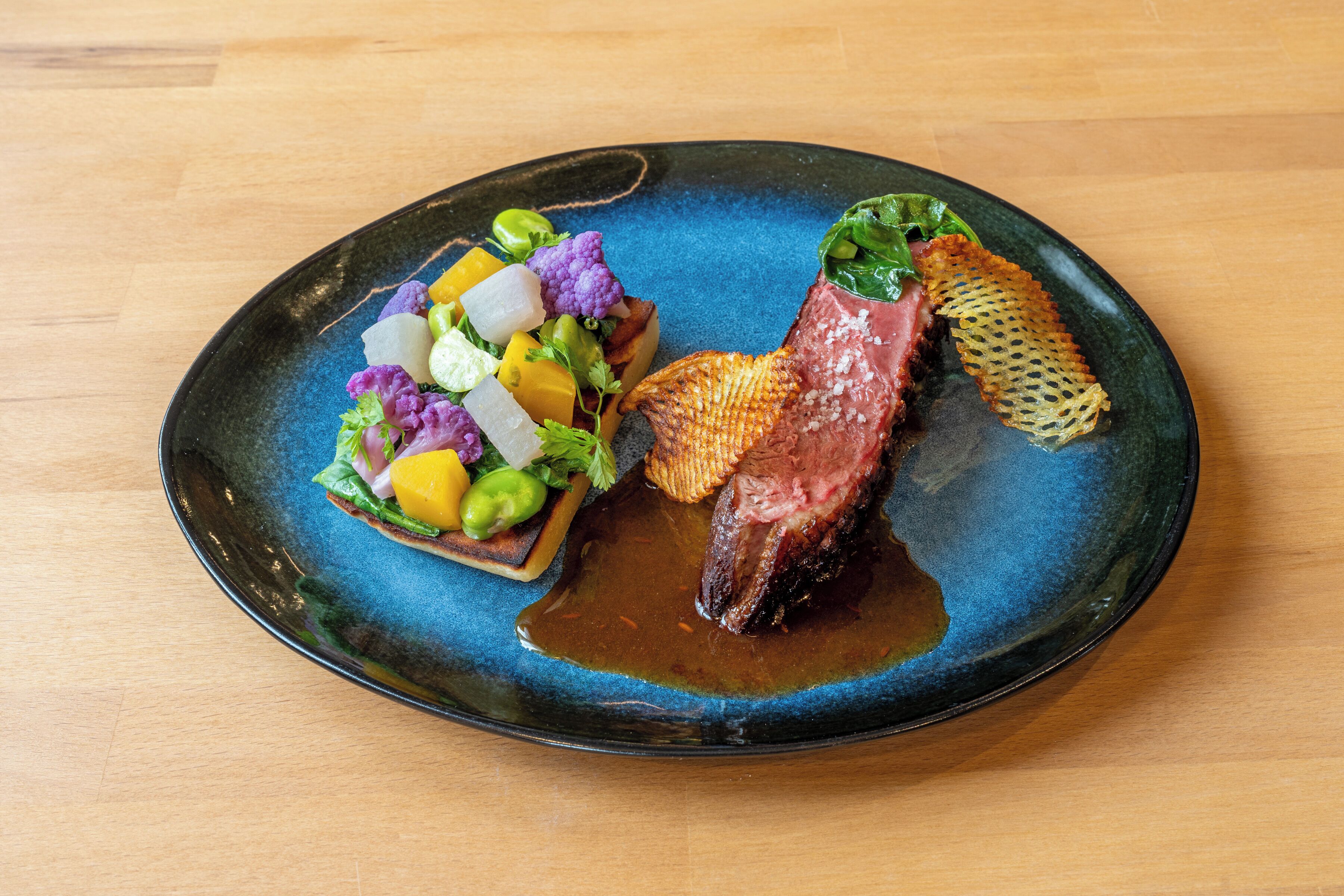Prato com bife, legumes e um objeto decorativo.