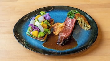 Un plato con un bistec, verduras y un adorno.