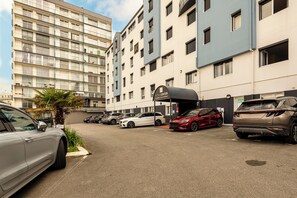 Un hôtel à plusieurs étages, un parking contenant plusieurs voitures et un panneau indiquant le centre de l’hôtel.