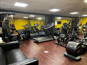 Une salle de sport équipée de tapis de course, de vélos elliptiques et de matériel de musculation.