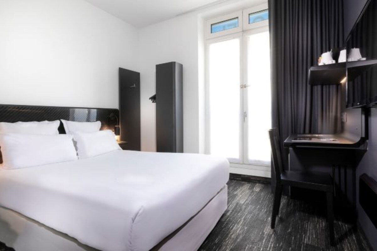 Een hotelkamer met een bed, een bureau, een stoel en een kledingkast.