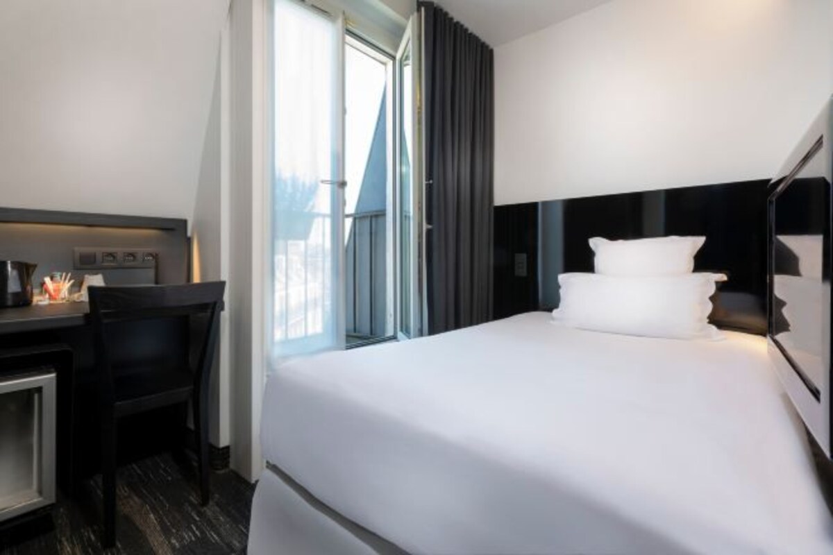 Quarto de hotel com uma cama, uma mesa e uma cadeira.