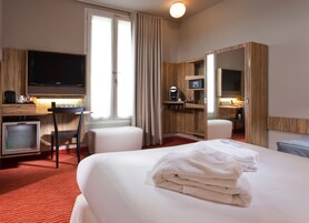 Habitación de hotel con cama, escritorio, televisor, minibar y baño.