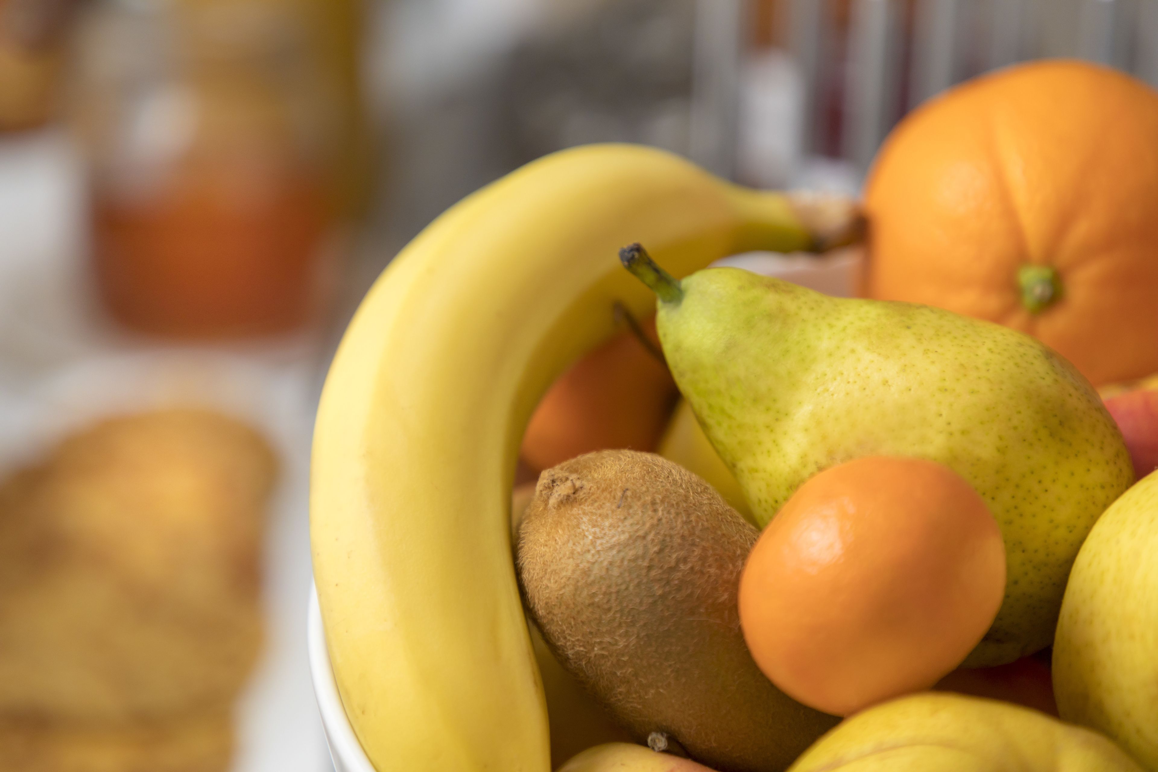 A bowl of fruit including bananas, pears, kiwis, and oranges.