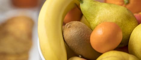 A bowl of fruit including bananas, pears, kiwis, and oranges.