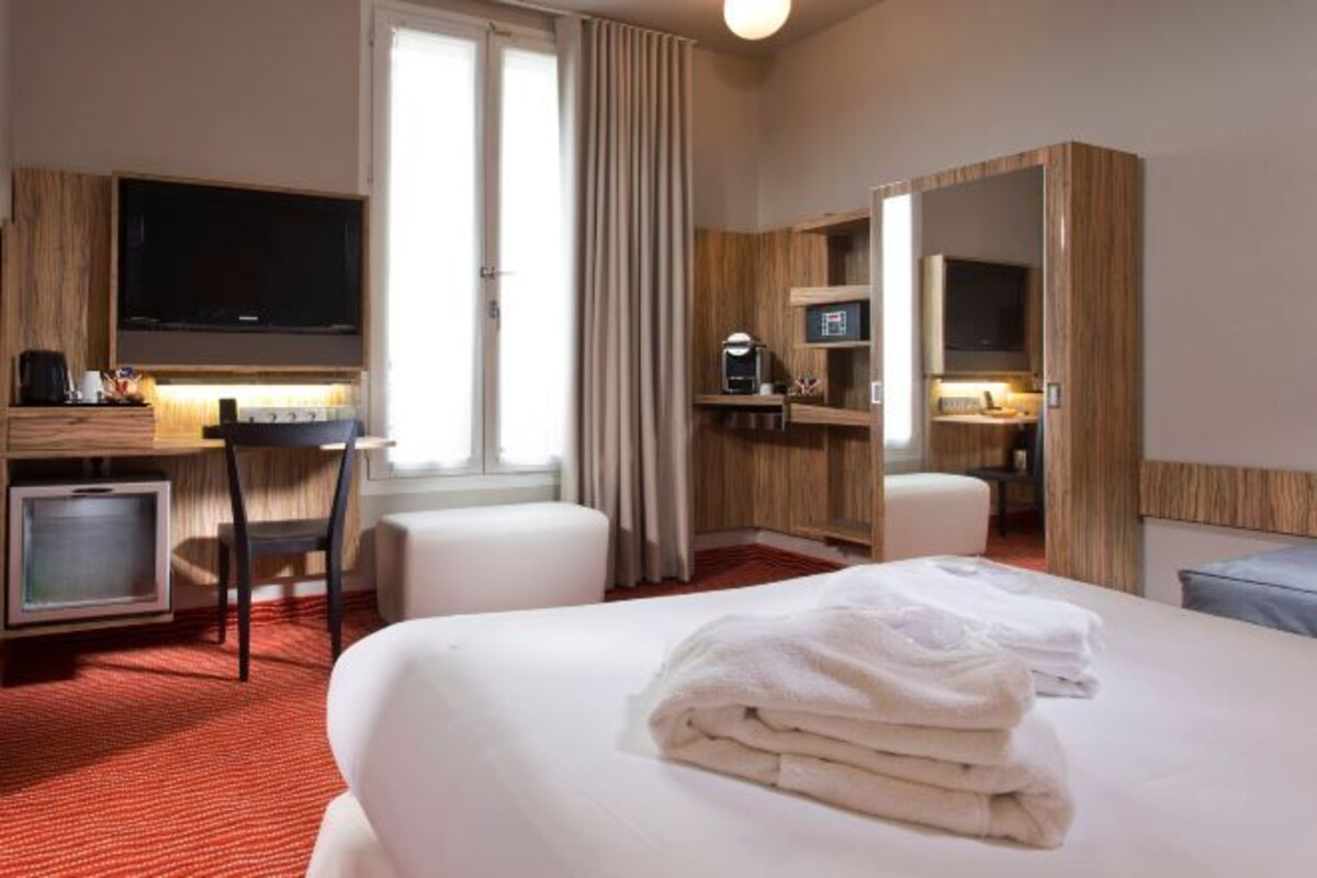 Een hotelkamer met een bed, bureau, televisie en badkamer.