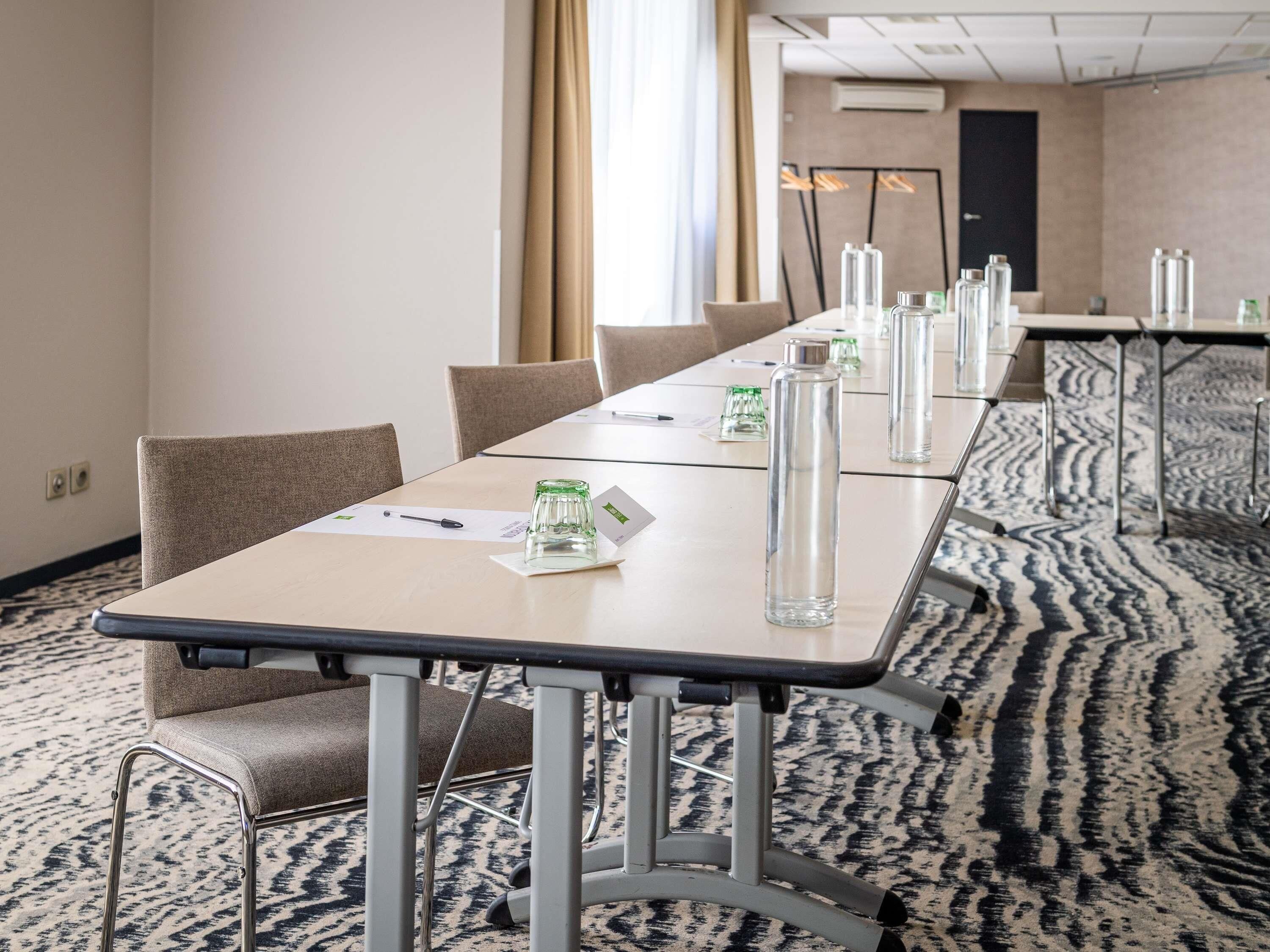 A conference room with a long table, chairs, and a patterned carpet.