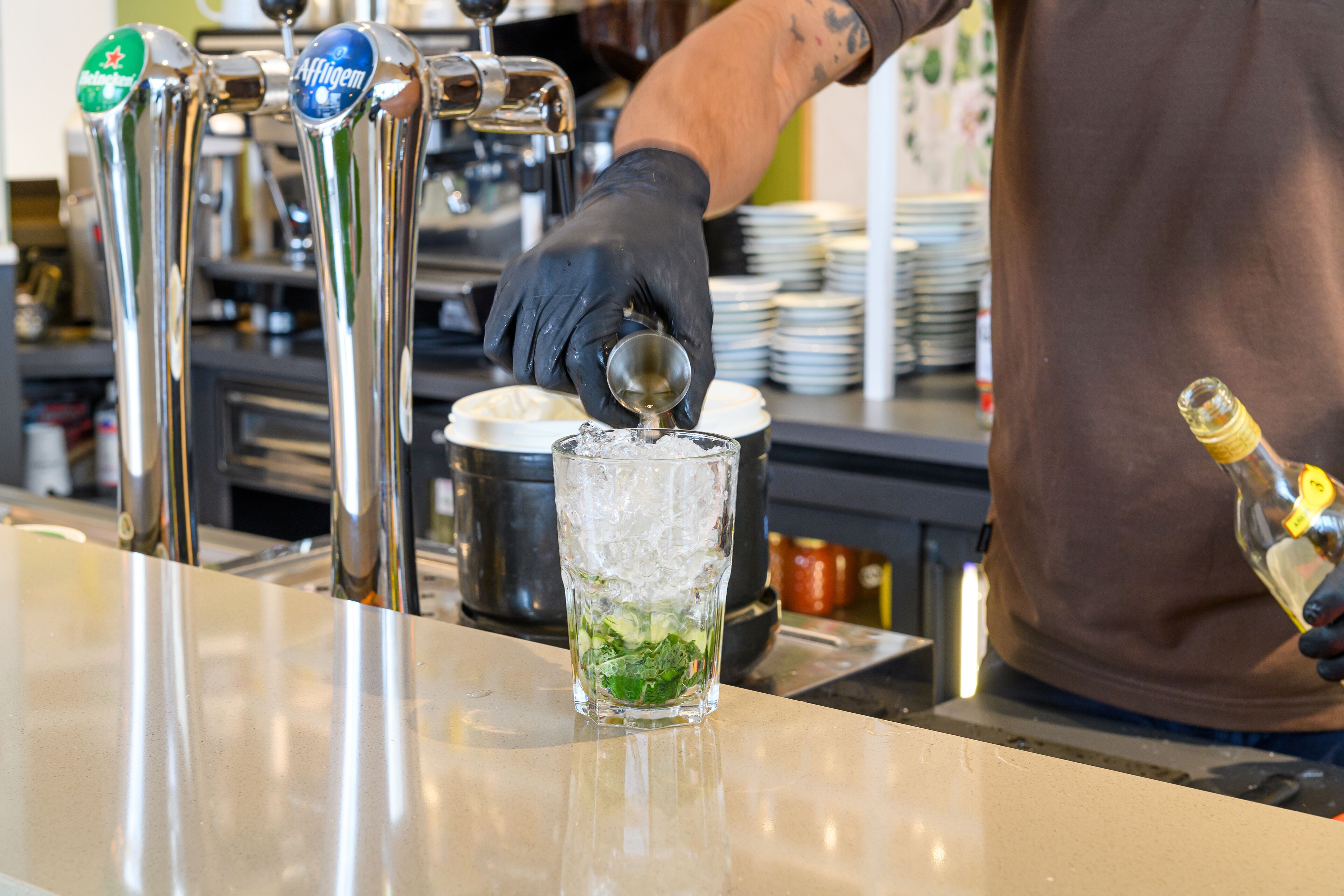 Un barista sirviendo una bebida en un vaso.