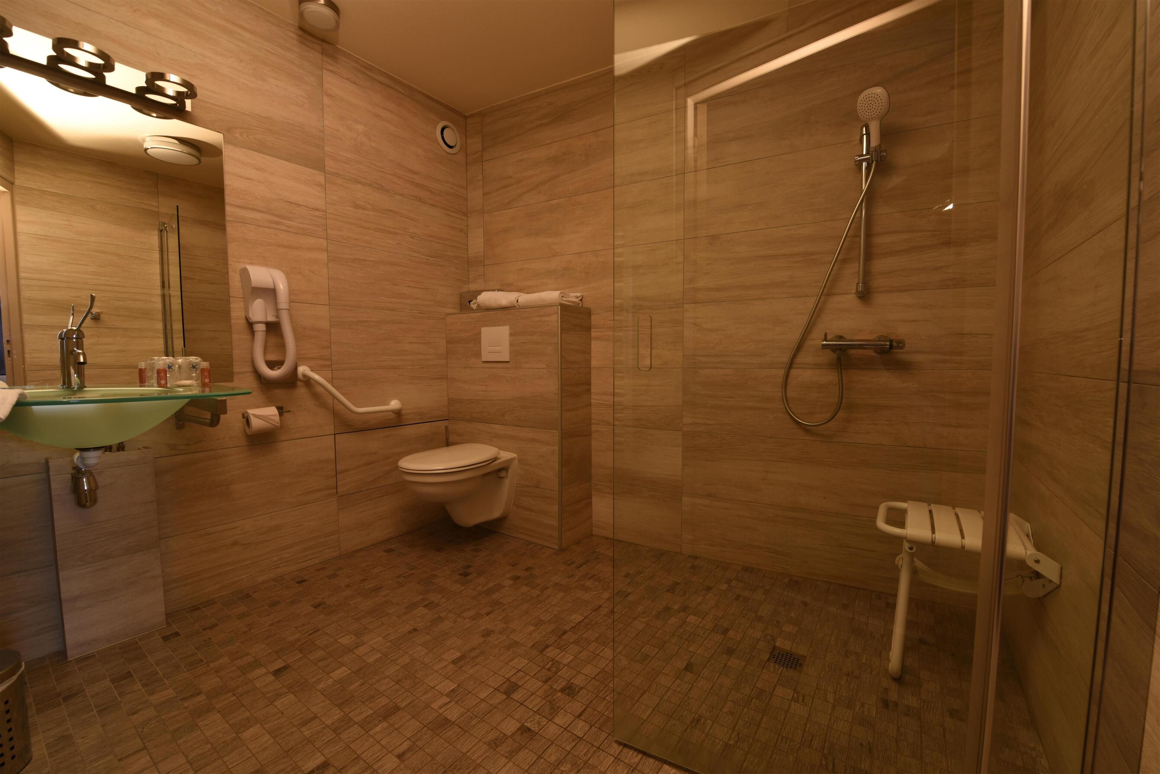 Une salle de bain avec une douche à parois de verre, des toilettes, un lavabo avec un récipient en verre et un miroir.