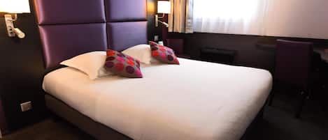 Una habitación de hotel con una cama grande, un escritorio y una silla.