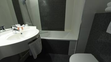 Een badkamer met een wit wastafel, een bad en een toilet.