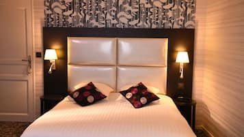 Habitación de hotel con una cama grande, dos lámparas de noche y un papel pintado estampado.