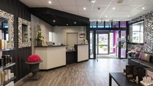 A reception area with a counter, a seating area with a sofa, and a decorative vase with pink flowers. - Relais St Eloi, Sure Hotel Collection by Best Western (Tours)