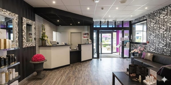 A reception area with a counter, a seating area with a sofa, and a decorative vase with pink flowers. - Relais St Eloi, Sure Hotel Collection by Best Western (Tours)