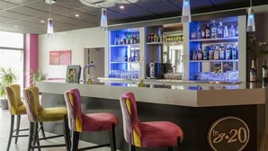 A bar area with a counter, bar stools, shelves with bottles, and a logo on the counter. - Relais St Eloi, Sure Hotel Collection by Best Western (Tours)