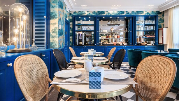 A dining area with blue walls, wicker chairs, and a checkered floor.