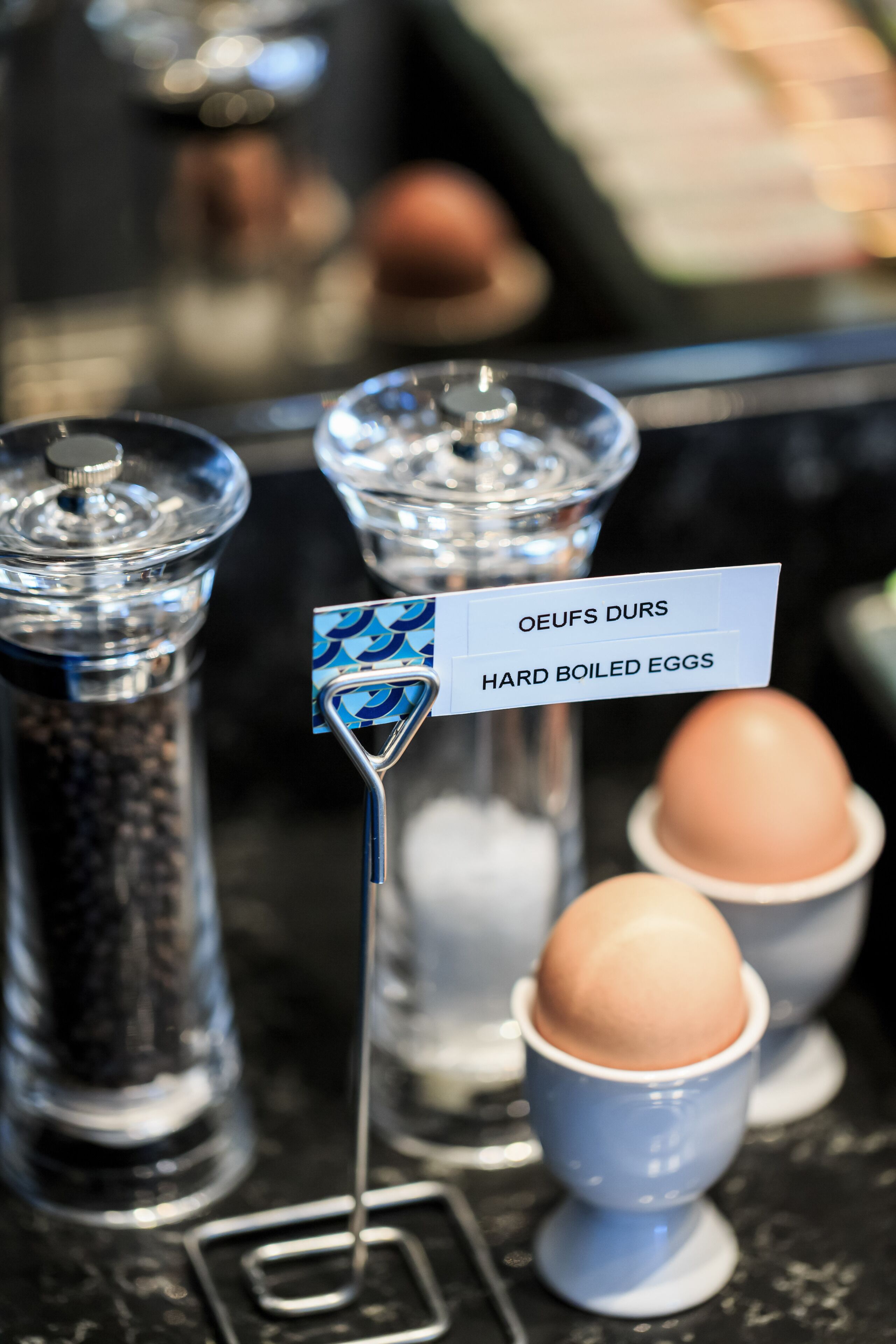 A display of hard-boiled eggs with a sign labeled "OEUFS DURS" in a kitchen setting.