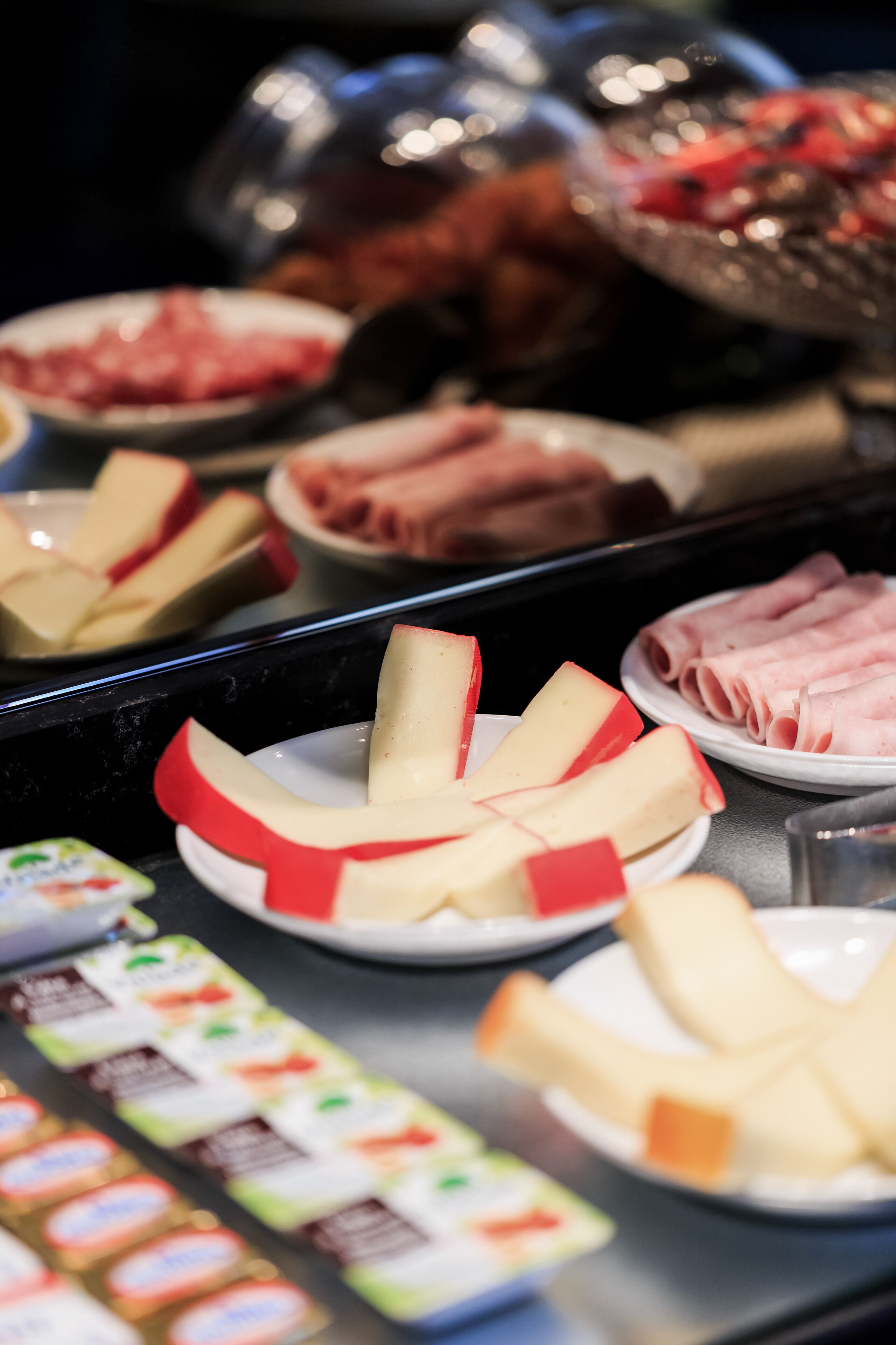 Un buffet proposant une variété d’aliments, notamment du fromage, du jambon et d’autres charcuteries.