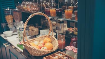 A breakfast buffet with a wicker basket filled with fruits, a variety of beverages, and a selection of pastries.