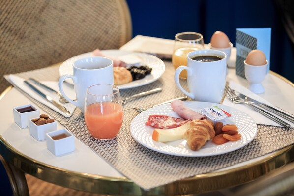 A breakfast table with croissants, eggs, juice, and a plate of yogurt and cheese. - Villa Otero by Happyculture (Nice)