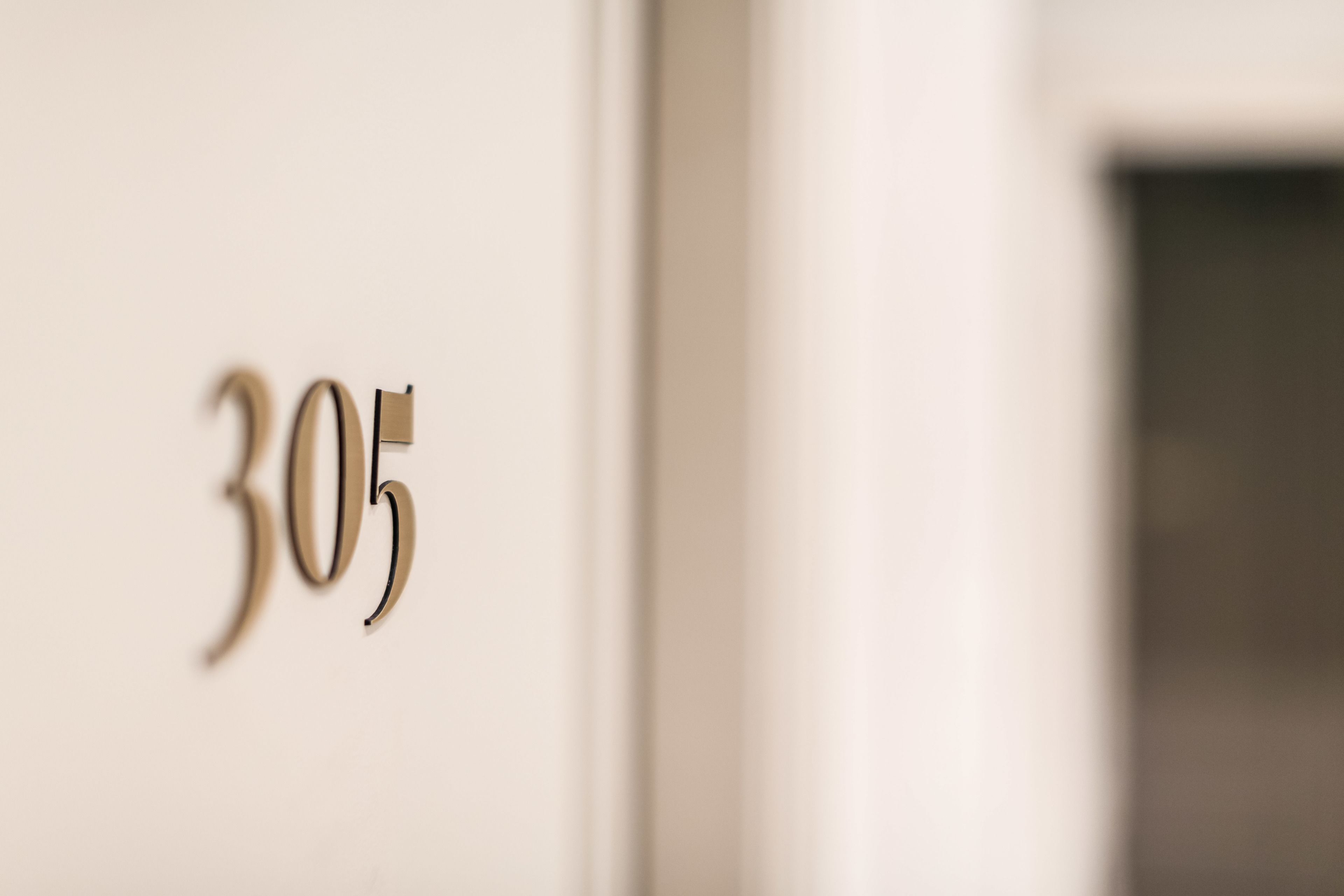 Een close-up van een kamer nummer 305 op een muur.