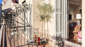 A balcony with a table, chairs, and a small tree.