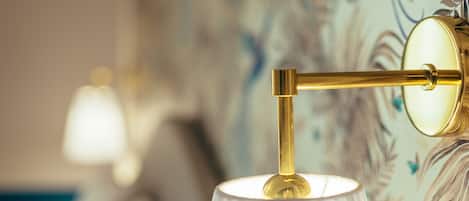 A close-up of a wall-mounted lamp with a white lampshade and a gold-colored fixture.