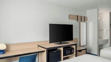 Camera d'albergo con un letto, una scrivania con televisore, un forno a microonde, un cestino e uno specchio.