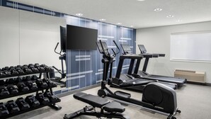 Un gimnasio con cintas de correr, elípticas y mancuernas.