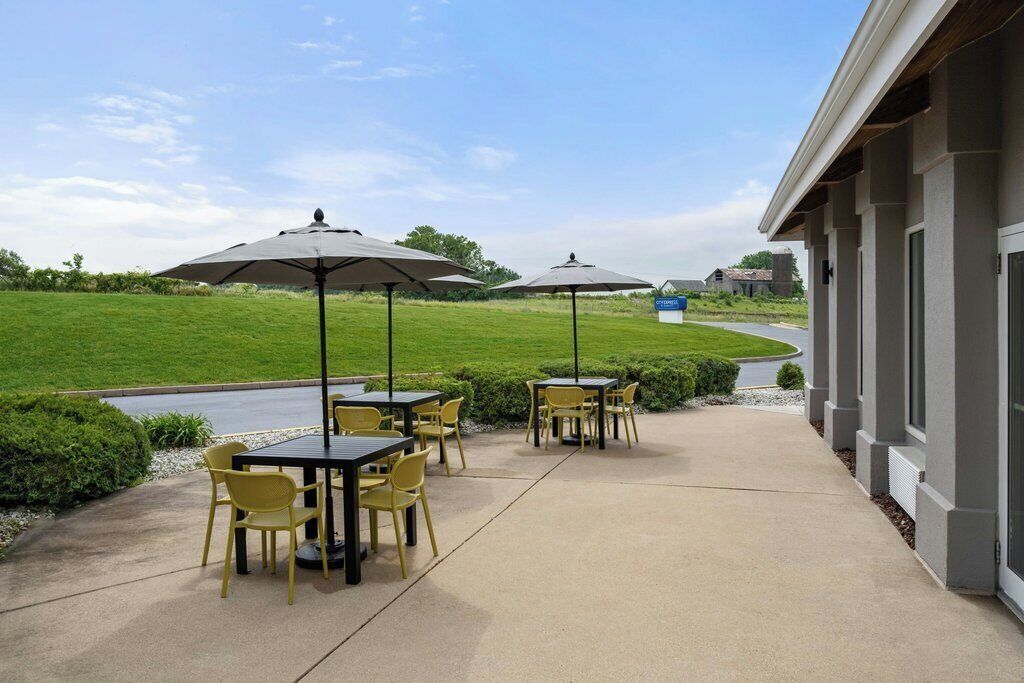 Un espace extérieur aménagé en terrasse, avec des tables et des chaises, des parasols et une vue sur un paysage verdoyant.