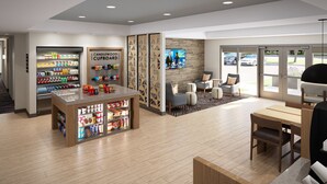 A modern lobby with a coffee shop, seating area, and a TV screen displaying a news program. - Candlewood Suites Rowlett - Lake Ray Hubbard by IHG (Rowlett)