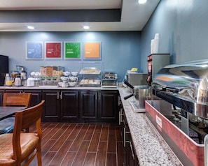 A breakfast bar with various food items, a coffee machine, and a microwave.