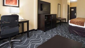 A hotel room with a desk, chair, TV, wardrobe, bed, and patterned carpet. - Candlewood Suites Rowlett - Lake Ray Hubbard by IHG (Rowlett)