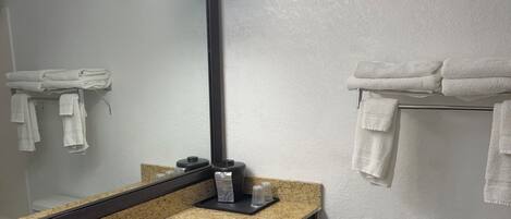 Un baño con lavamanos de encimera de granito, un espejo, toallero y retrete.