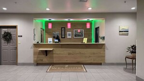 A reception desk with a 'WELCOME' mat, framed pictures on the wall, and a 'DOOR' sign. - Country Inn & Suites by Radisson, Elgin, IL (Elgin)