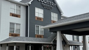 A Country Inn & Suites building with a dark exterior, multiple windows, and a covered entrance area. - Country Inn & Suites by Radisson, Elgin, IL (Elgin)
