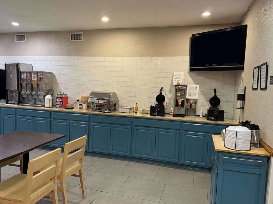 A kitchen with blue cabinets, a coffee machine, a microwave, and a flat-screen TV mounted on the wall.